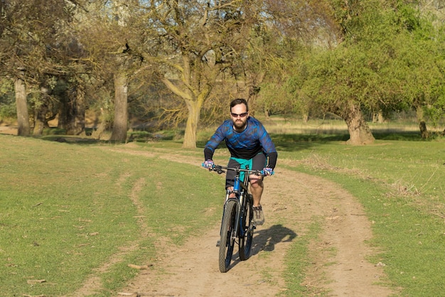 Sports brutal bearded guy on a modern mountain bike Cyclist on the green hills in the spring