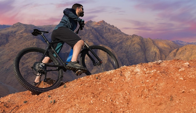 現代のマウンテンバイクでスポーツの残忍なひげを生やした男湖のほとりの塩の人里離れた場所にいるサイクリスト