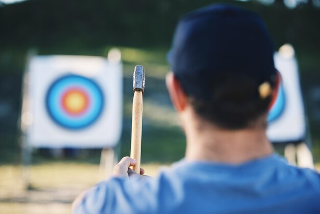 Foto bullseye sportivo e uomo con ascia per bersaglio a portata di mano per esercizi di allenamento e gare di caccia il fitness sportivo estremo e l'arciere maschio mirano con l'arma tomahawk per giochi di pratica e avventura