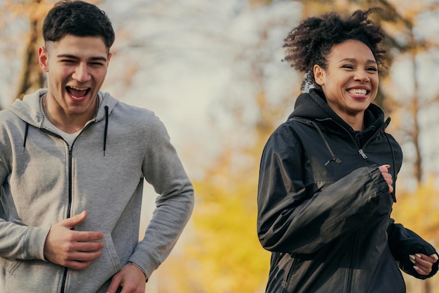 Sports couple in love happy young man and woman of different\
ethnics do sports fitness cardio