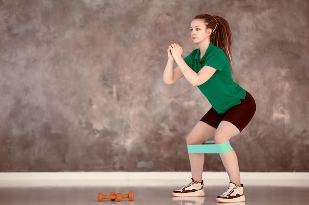 Sports elastic band for training on legs of serious caucasian woman in gym