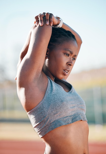 Sports exercise and woman stretching outdoor at a stadium for workout training and warm up African athlete person for muscle stretch fitness and wellness or flexibility for a run or competition