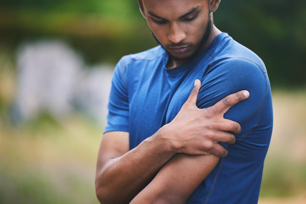 Photo sports fitness and man with pain in shoulder after workout exercise and marathon training outdoors medical emergency health and male person with muscle strain arm injury and joint ache in park