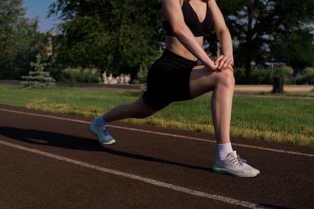 街のスポーツグラウンドで朝のトレーニングやストレッチをしているスポーツガールスポーツに関するフィットネストレーニング