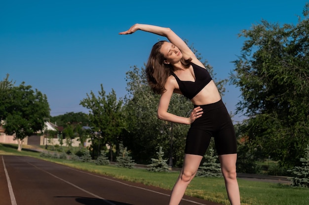 Sports girl doing morning workout and stretching on street sports ground Fitness training on sports