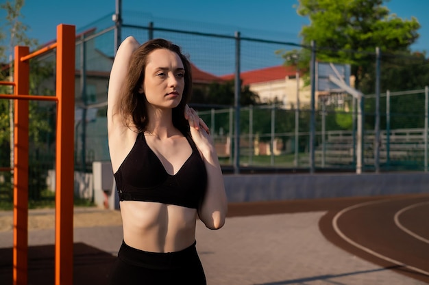 Sports girl doing morning workout and stretching on street sports ground Fitness training the sports