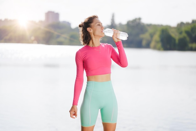 スポーツ少女は都市公園でのトレーニング後に水を飲む