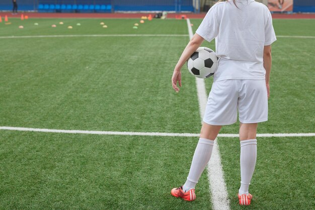 여자 축구 선수가 축구장 위에 축구공을 들고 있는 여자 스포츠 선수, 프로 여자 축구의 개념