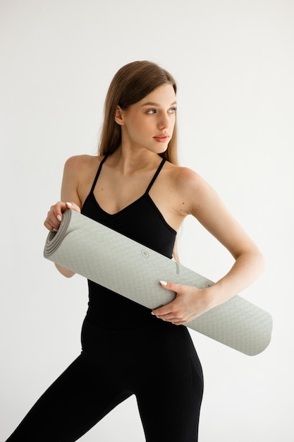 Sports girl holding a fitness mat in her hands on a white background