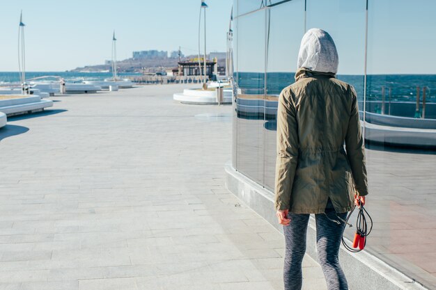 Sports girl in a hood walking along the coast