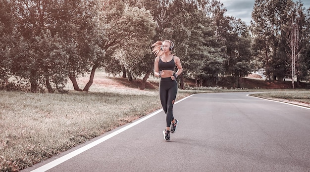 Ragazza sportiva che fa jogging nel parco il concetto di uno stile di vita sano attrezzatura sportiva pubblicità in stile fitness