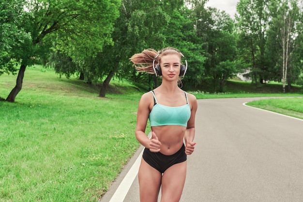 Ragazza sportiva che fa jogging nel parco il concetto di uno stile di vita sano attrezzatura sportiva pubblicità in stile fitness