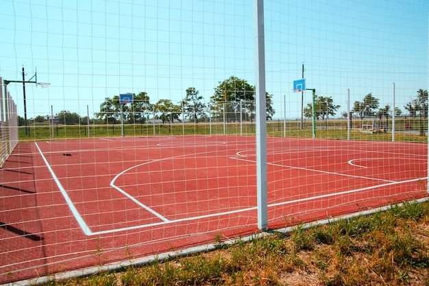 Спортивная площадка для детей и взрослых. Искусственный газон. Баскетбольная площадка огорожена забором.