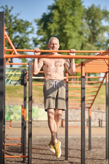 Sports ground. A gray-haired mature man having a workout on the open sports ground