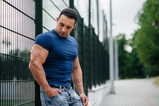 Sports guy stands near the sports field. Bodybuilding