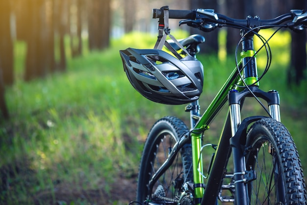 Mette in mostra il casco su una mountain bike verde nel parco. protezione del concetto durante uno stile di vita attivo e sano