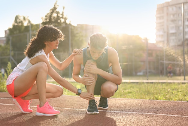 Sports injury Woman helping man with leg pain at stadium space for text