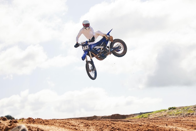 Спортивный прыжок и мужчина на мотоцикле со свободой энергии и силовым трюком в сельской местности для тренировок Внедорожный воздух и мужские прыжки с мотоциклом для скоростных характеристик или мото действий