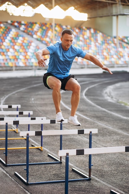 Sports man jumping over barriers at the stadium