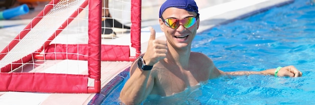 Sports man in the pool smiling and showing thumbs up