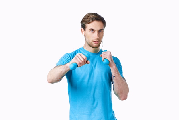 Sports man with dumbbells in hands workout fitness light background