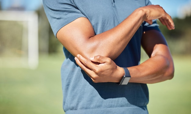 Sports man with elbow pain on arm injury in outdoor soccer field Hand massage bone person with emergency muscle problem physiotherapy in sport and joint accident with physical therapy