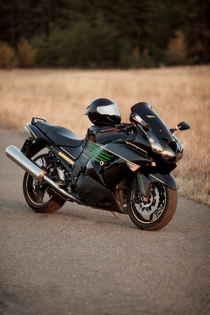 Foto moto sportiva e casco di sicurezza su di esso sulla strada con un bellissimo sfondo di foresta