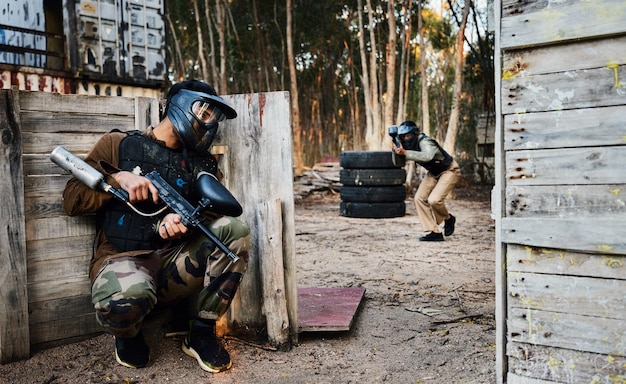 Sports paintball and man with gun for battle game or competition outdoors on field War military camouflage and male soldier with weapon on shooting range to hide from player in exercise fight