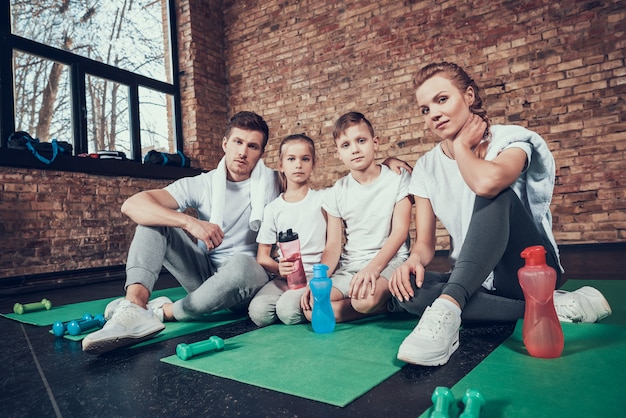 Sports people sit on the green mat in the gym