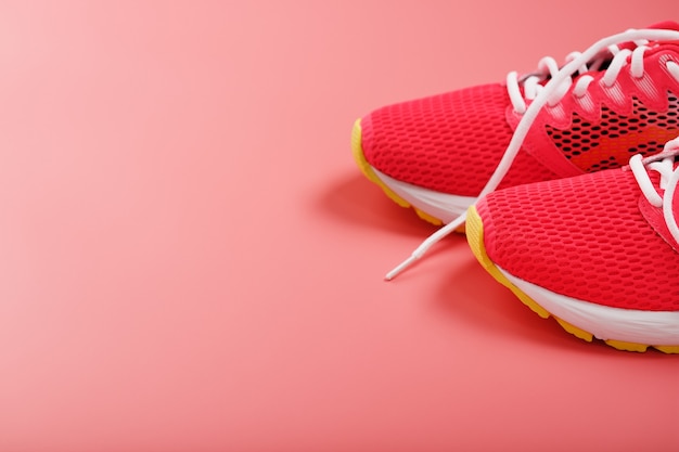 Sports pink sneakers on a pink background with free space. Top view, minimalistic concept
