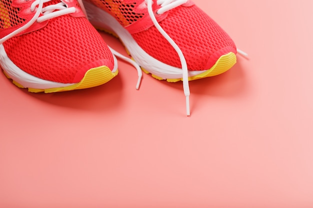 Sports pink sneakers on a pink background with free space. Top view, minimalistic concept