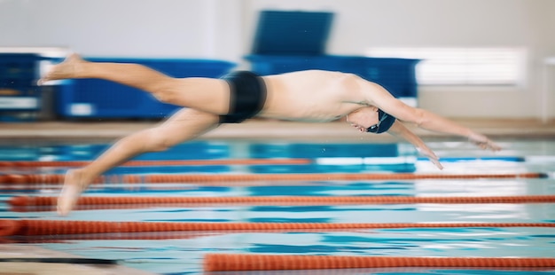 Sports pool and male athlete diving for training exercise or competition for indoor swimming Fitness action and young man swimmer doing a dive jump for a cardio workout or water sport gala