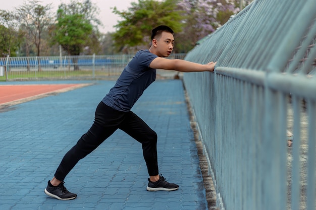 Sports and recreation concept a male youth doing warm-up by\
stretching each part of his body as preparation before\
exercise.