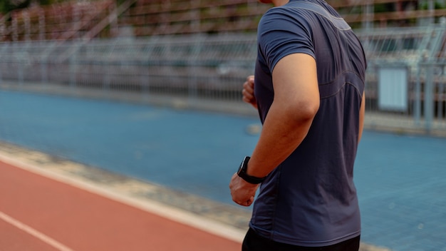 Concetto di sport e ricreazione un giovane maschio adulto che corre a bassa velocità nello stadio sportivo come la sua sana routine serale.