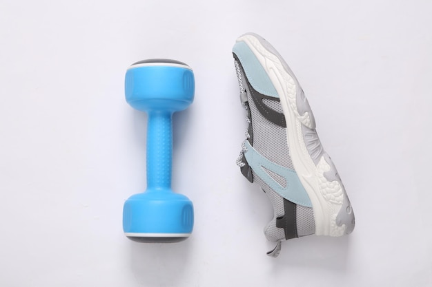 Sports shoe and dumbbell on gray background Fitness concept Top view Minimalism