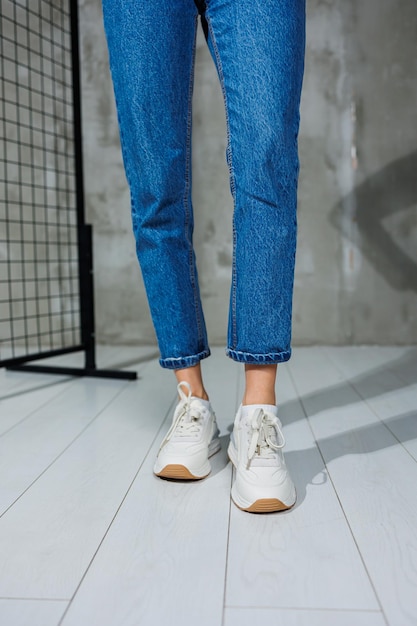 Спортивная обувь для женщин Стройные женские ножки в джинсах и белых стильных повседневных кроссовках Женская удобная летняя обувь Повседневная женская мода