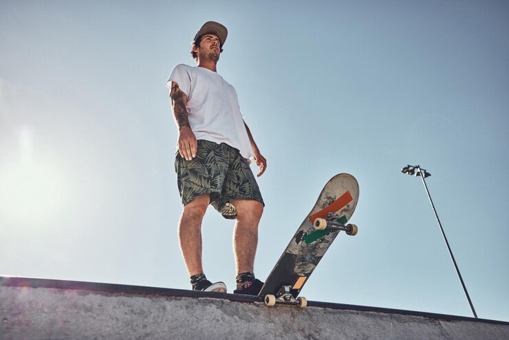 Photo sports skater and low angle of man on ramp preparing for action stunt trick or practice in city thinking skateboarding and male skateboarder getting ready for training or workout at a skate park