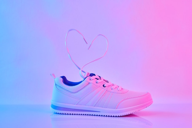 Sports sneakers with heart-shaped laces in neon light.  Flying shoelaces.