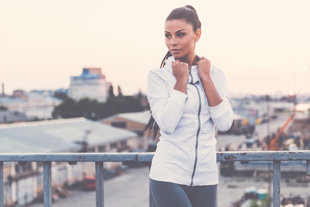 Sports style. Beautiful young woman adjusting her sports clothes and looking away 