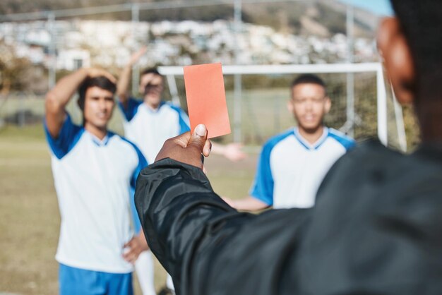 Photo sports team red card and soccer referee outdoor on field for game foul mistake or compliance football player athlete club and paper in person hand for sport warning penalty rules or dismissal