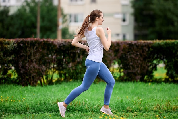 Sports training of female runner in public park next to residential area and an apartment building
