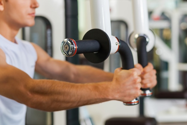 Sports training in gym. Concentrated young and sporty man working out in gym