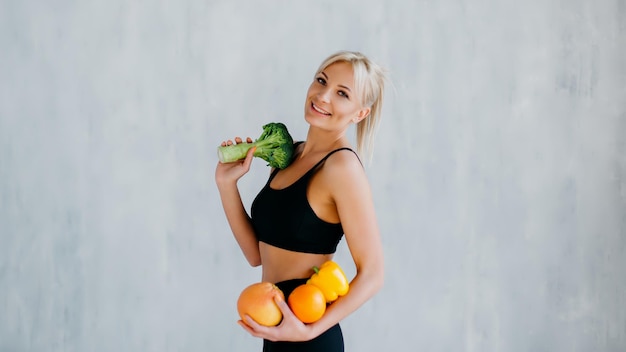 Sports woman holding fresh fruits and vegetables in hands healthy eating concept