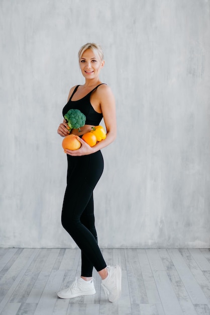 Sports woman holding fresh fruits and vegetables in hands healthy eating concept