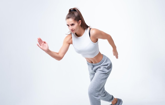 Sports woman runner on a white background Photo of an attractive woman in fashionable sportswear Dynamic movement Side view Sports and healthy lifestyle