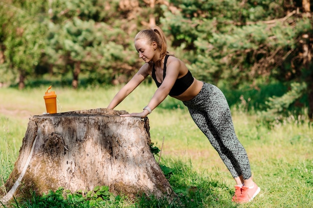 Donna sportiva in tuta sportiva che fa esercizi all'aperto nel parco