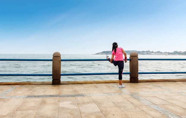 Sports women stretch their legs on the beach in the morning