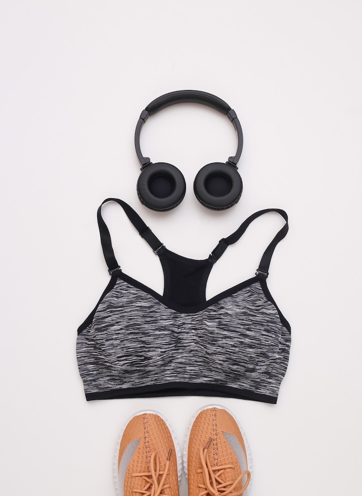 Foto sportschoenen, top beha en stereo koptelefoon op witte achtergrond. sport- en fitnessconcept. bovenaanzicht. plat leggen