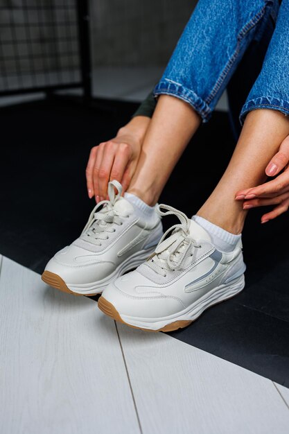 Sportschoenen voor dames Slanke vrouwelijke benen in jeans en witte stijlvolle casual sneakers Comfortabele zomerschoenen voor dames Casual damesmode