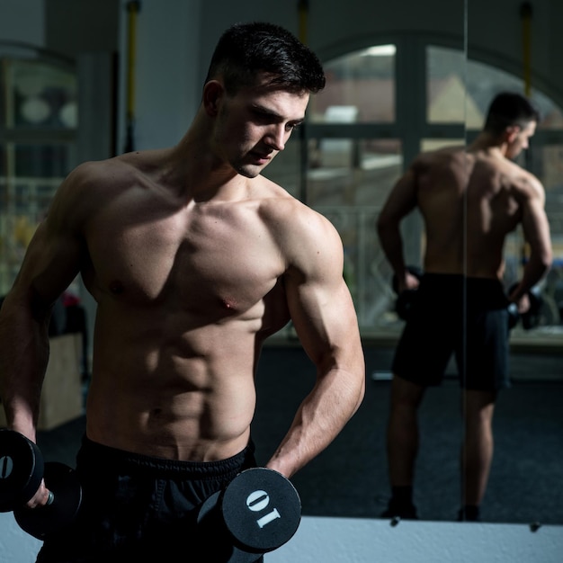 Sportsman athlete with muscles looks attractive Man with torso muscular macho and his reflexion in mirror backgroundMan with nude torso in gym enjoy his sporty lifestyle Sport and gym concept